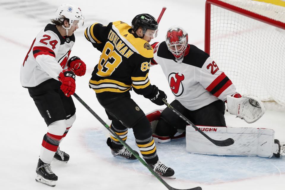 Boston Bruins' Karson Kuhlman (83) cannot get a shot off against New Jersey Devils' Ty Smith (24) and Mackenzie Blackwood (29) during the first period of an NHL hockey game, Sunday, March 28, 2021, in Boston. (AP Photo/Michael Dwyer)