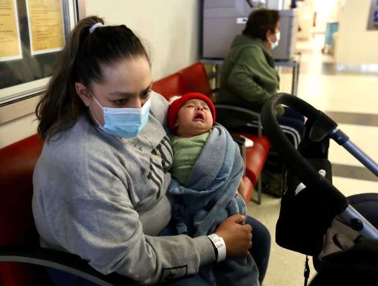 A woman sits with her son , in the emergency room of a hospital.