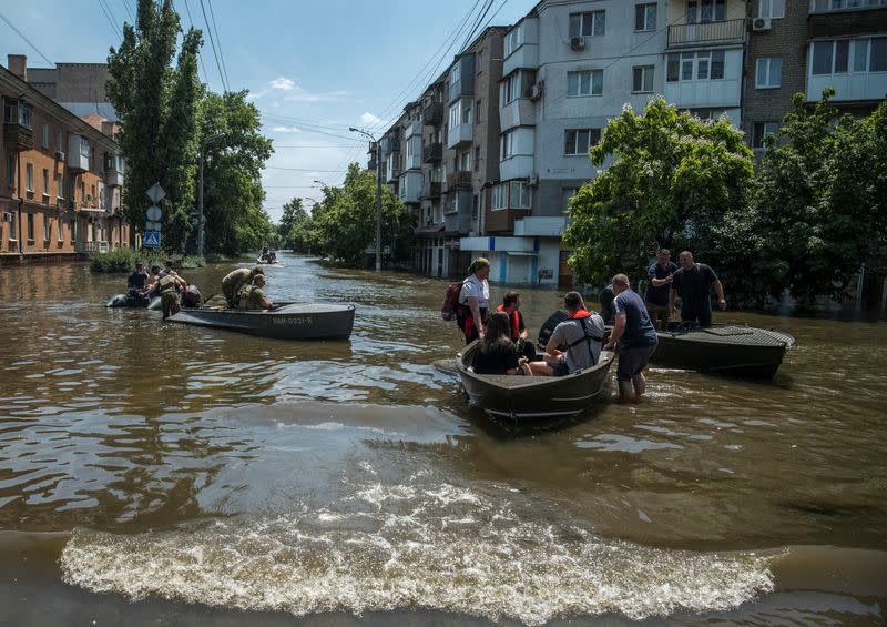 Rescuers, servicemen and volunteers evacuate local residents from a flooded area after the Nova Kakhovka dam breached, in Kherson