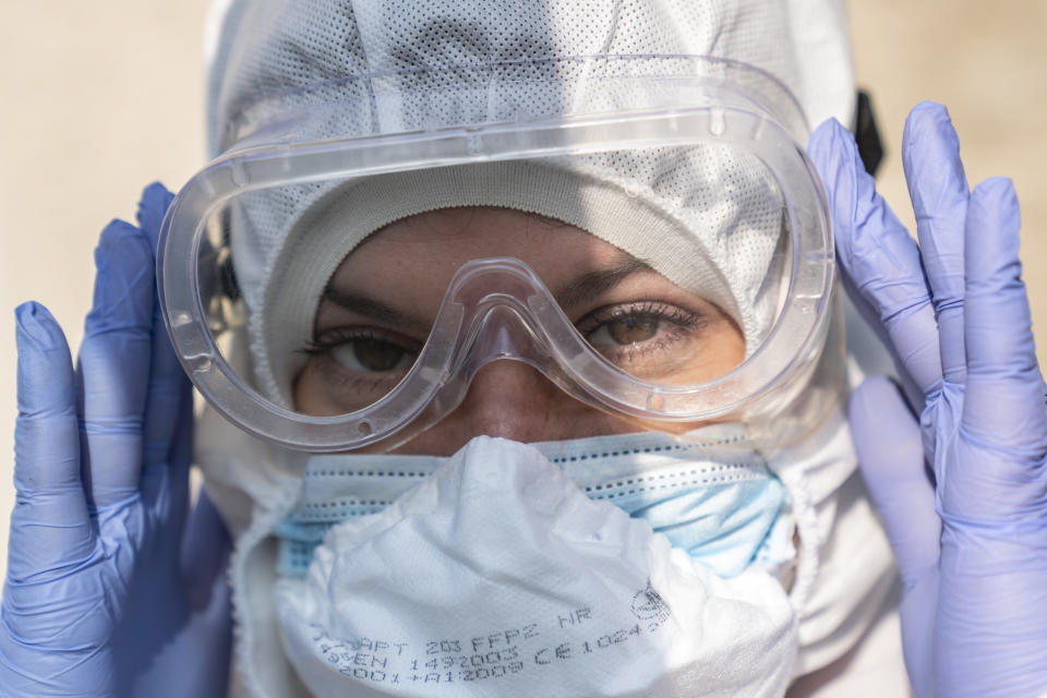 In this photo taken on Saturday, May 9, 2020, ambulance medic Svetlana Padynich, puts on protective goggles at the start of her ambulance shift at an ambulance station in Chernivtsi, Ukraine. Ukraine's underfunded health care system was quickly overwhelmed by the coronavirus, with medics accounting for one fifth of all coronavirus cases in the country. (AP Photo/Evgeniy Maloletka)