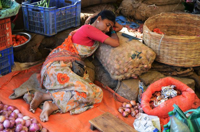 An Indian market trader takes a rest in the sweltering heat at her vegetable stall in Hyderabad on May 22, 2015