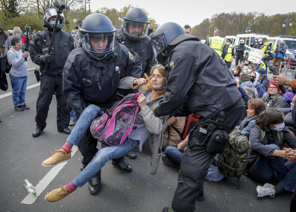 Police officers carry away a demonstrator after police stop a protest rally against the German government's policy to battle the corona virus pandemic in Berlin, Germany, Wednesday, April 21, 2021.The parliament decides on a law that gives the federal government more power to battle the coronavirus pandemic. (AP Photo/Markus Schreiber)