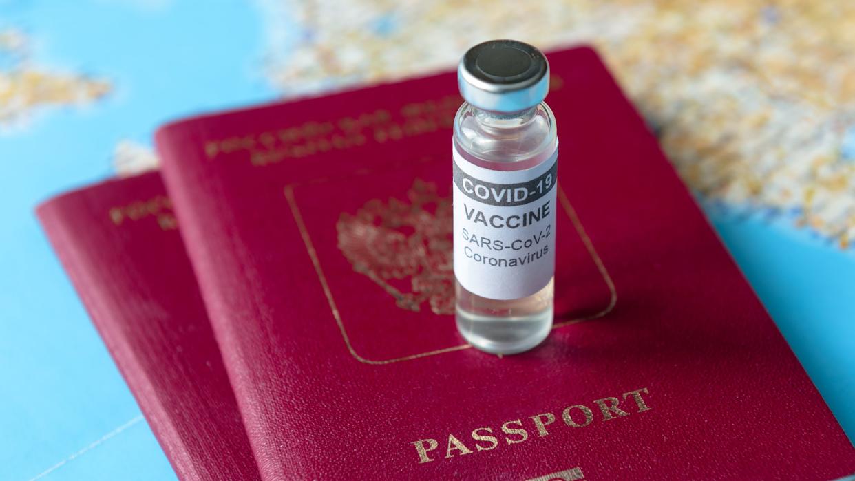 Travel during COVID-19 pandemic, bottle of coronavirus vaccine and passports on tourist map. World tourism hit by corona virus during pandemic. Concept of COVID vaccine, restrictions and lockdown.