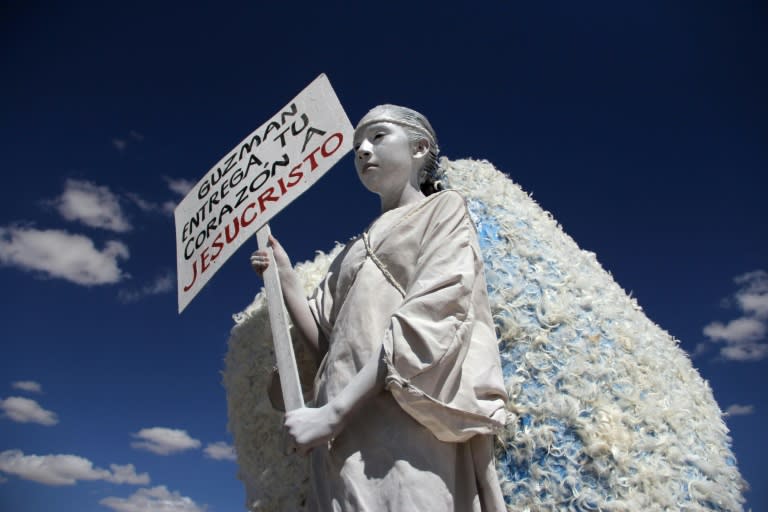 A young woman carries a sign urging drug lord Joaquin "El Chapo" Guzman to give his heart to Jesus Christ, outside of the Cefereso No. 9 prison where he is serving time in Ciudad Juarez, Mexico on September 24, 2016