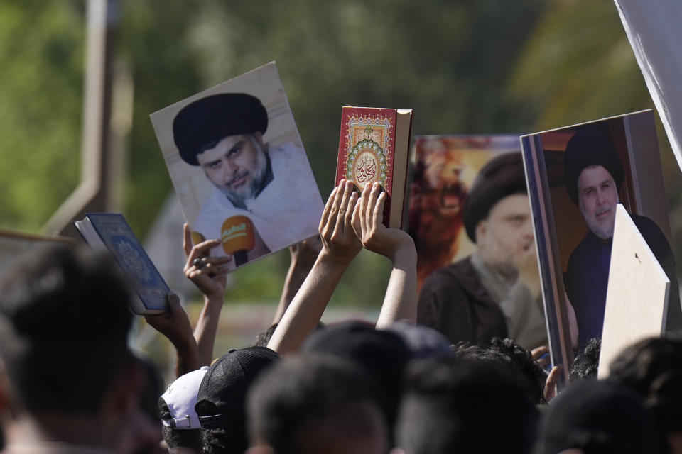 Supporters of the Shiite cleric Muqtada al-Sadr raises of the Quran, the Muslims' holy book, during a demonstration in front of the Swedish embassy in Baghdad in response to the burning of Quran in Sweden, Baghdad, Iraq, Friday, June 30, 2023. (AP Photo/Hadi Mizban)