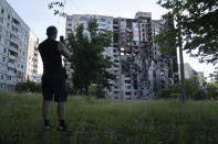 FILE - A man takes a photo using his phone of a building which had been destroyed in a Russian attack in Kharkiv, Ukraine, July 1, 2022. As Russia's invasion of Ukraine grinds into its fifth month, some residents close to the front lines remain in shattered and nearly abandoned neighborhoods. One such place is Kharkiv's neighborhood of Saltivka, once home to about half a million people. Only perhaps dozens live there now, in apartment blocks with no running water and little electricity. (AP Photo/Evgeniy Maloletka, File)