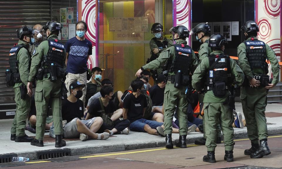 People, sitting on the ground, are arrested by police officers at a downtown street in Hong Kong Sunday, Sept. 6, 2020. About 30 people were arrested Sunday at protests against the government's decision to postpone elections for Hong Kong's legislature, police and a news report said. (AP Photo/Vincent Yu)