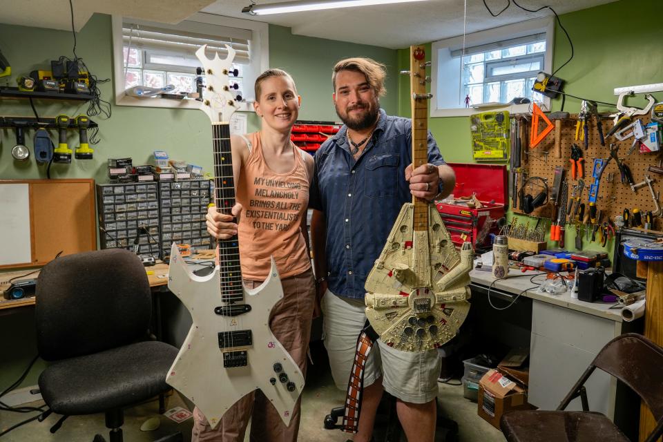 Luna Cherry, left, and husband Devin Cherry hold some of the more complex guitars they’ve crafted at the Cherrys' home in West Price Hill. Luna’s Sorceress guitar took her over a year to build with hand drawn symbols, while Devin’s is a Millennium Falcon guitar he made from the model of the spaceship when he was younger.