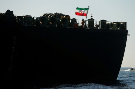 A crew member raises the Iranian flag on Iranian oil tanker Adrian Darya 1, previously named Grace 1, as it sits anchored after the Supreme Court of the British territory lifted its detention order, in the Strait of Gibraltar