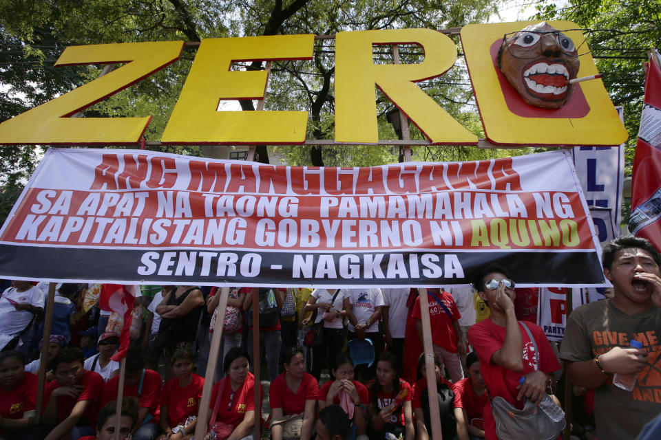 Workers shout slogans as they hold a rally near the Presidential Palace to mark the Labor Day celebrations on Thursday, May 1, 2014 in Manila, Philippines. Various labor groups nationwide held protests, mostly to demand wage hikes, better working conditions and an end to corruption in the government. The sign reads: Workers Have Zero Benefits In The Four Years of Capitalist Government of Aquino. (AP Photo/Bullit Marquez)