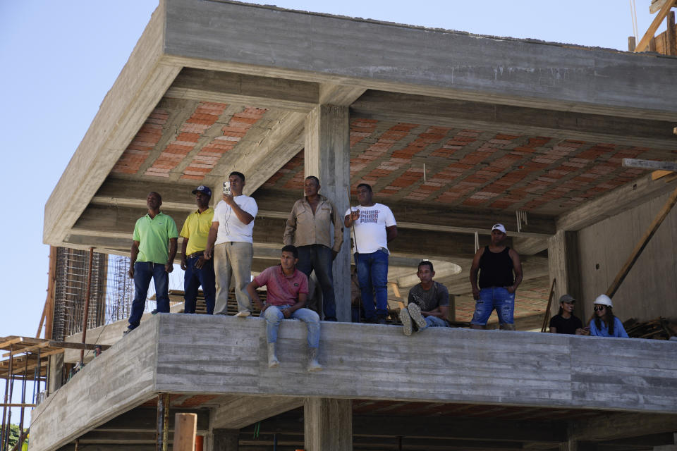 Construction workers pause during a press conference by opposition coalition presidential hopeful Maria Corina Machado held in the street below them, outside her campaign headquarters in Caracas, Venezuela, Monday, Jan. 29, 2024, days after the country's highest court upheld a ban on her candidacy. (AP Photo/Ariana Cubillos)