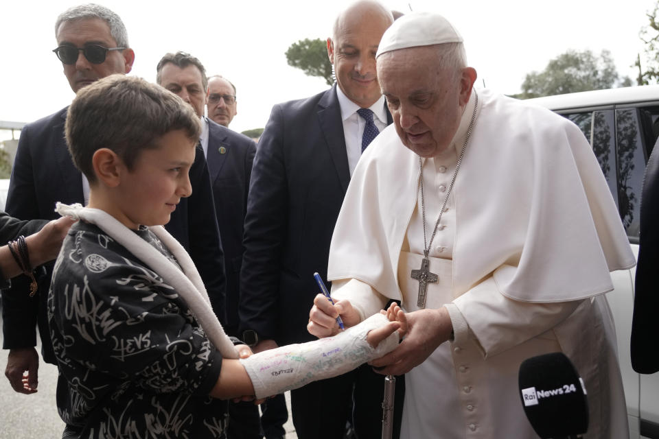 Pope Francis autographs the plaster cast of a child as he leaves the Agostino Gemelli University Hospital in Rome, Saturday, April 1, 2023, after receiving treatment for bronchitis, The Vatican said. Francis was hospitalized on Wednesday after his public general audience in St. Peter's Square at The Vatican. (AP Photo/Gregorio Borgia)