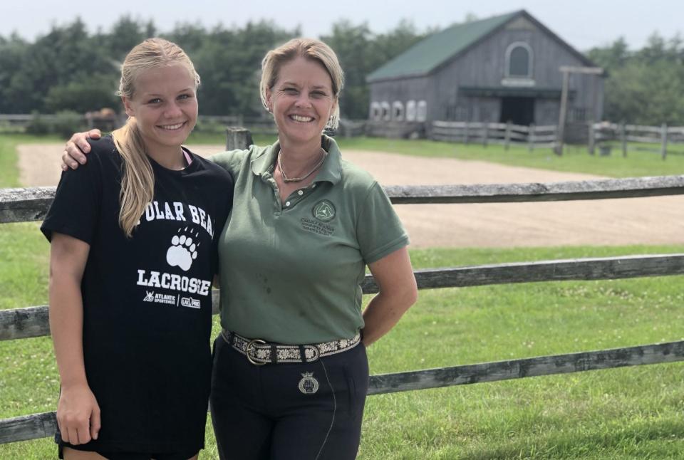 Sarah Armentrout, right, the head of Carlisle Academy, is seen here with her daughter, Ivy, at their home at Spring Creek Farm in Lyman, Maine, on July 13, 2023. The academy, which now sprawls across the whole farm, started years ago at the structure behind them.