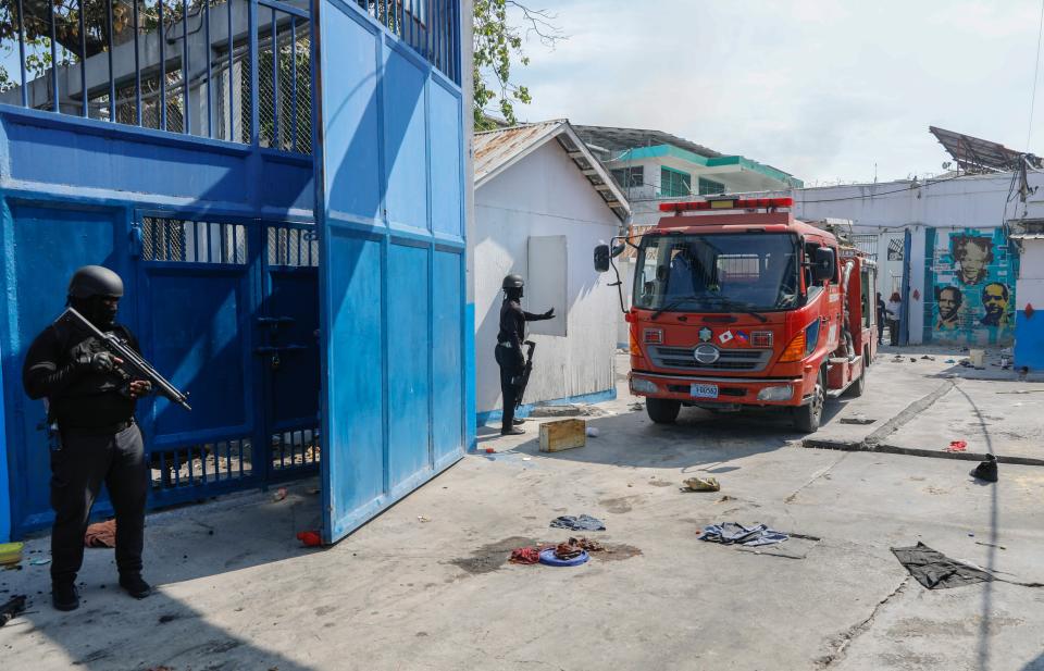 Firefighters arrive to put out a small fire at the empty National Penitentiary as National Police patrol in downtown Port-au-Prince, Haiti, Haiti, Thursday, March 14, 2024. This is the same facility that armed gangs stormed late March 2 and hundreds of inmates escaped. (AP Photo/Odelyn Joseph)
