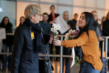 An opponent of U.S. President Donald Trump's executive order travel ban hands flowers to a member of a Lufthansa flight crew at Logan Airport in Boston, Massachusetts, U.S. February 3, 2017. The Lufthansa flight carried several Boston area college students who had previously been denied travel under the travel ban. REUTERS/Brian Snyder