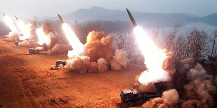 پنج موشک بزرگ به طور همزمان از پشت پرتابگرها در کره شمالی در 10 مارس 2023 در یک تصویر توزیع شده دولتی شلیک شدند که اینسایدر نتوانست آن را تأیید کند.  توده های دود در برابر زمین قرمز، در مقابل پس زمینه کوهی مه آلود برمی خیزند.
