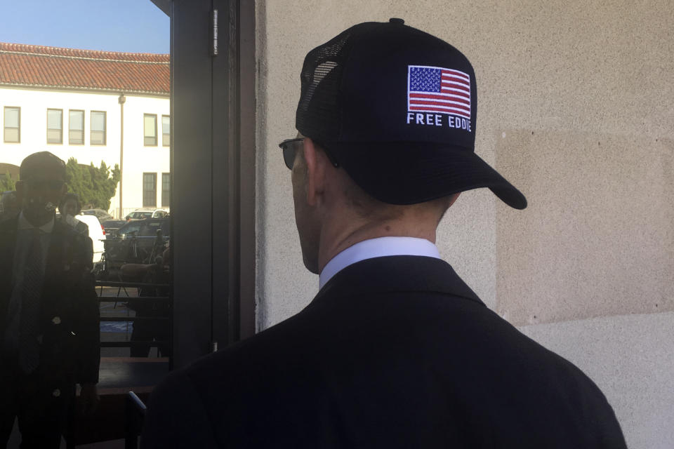 Marc Mukasey, defense lawyer for Navy Special Operations Chief Edward Gallagher, shows off a hat with the words, "free Eddie," as he arrives to military court on Naval Base San Diego, Tuesday, July 2, 2019, in San Diego. Jury deliberations continued Tuesday morning in the court-martial of the decorated Navy SEAL, who is accused of stabbing to death a wounded teenage Islamic State prisoner and wounding two civilians in Iraq in 2017. He has pleaded not guilty to murder and attempted murder, charges that carry a potential life sentence. (AP Photo/Julie Watson)
