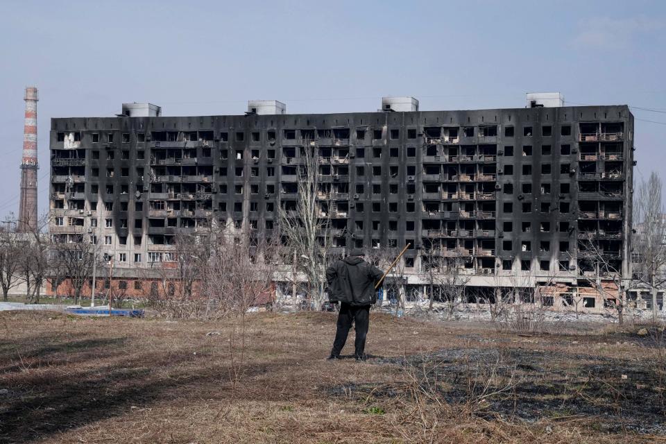 A man looks at a burned apartment building that was damaged by shelling in Mariupol, Ukraine, Sunday.