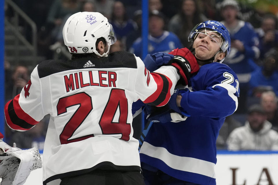 New Jersey Devils defenseman Colin Miller (24) and Tampa Bay Lightning center Brayden Point (21) scrap during the second period of an NHL hockey game Thursday, Jan. 11, 2024, in Tampa, Fla. (AP Photo/Chris O'Meara)