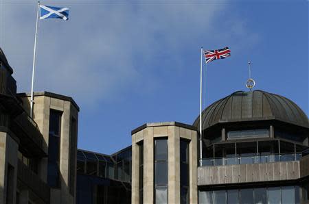 A Scottish Saltire flag (L) and a Union flag of the United Kingdom fly above Standard Life House in Edinburgh, Scotland February 27, 2014. Insurance and pensions heavyweight Standard Life became the first major company to warn it could move partly out of Scotland if Scots split from the United Kingdom, fuelling a political row over the financial impact of independence. REUTERS/Russell Cheyne