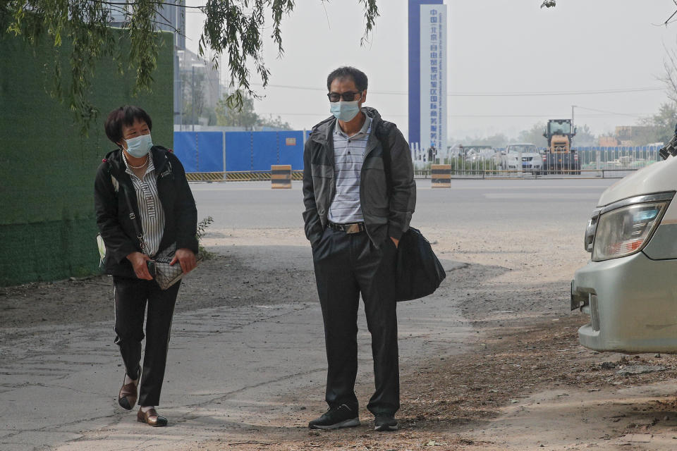 Wei Xiuwen, left, mother of Chen Mei, and Cai Jianli, center, father of Cai Wei arrive outside a courthouse to attend their children's court cases in Beijing, Tuesday, May 11, 2021. Two amateur computer coders taken by police from their Beijing homes last year were standing trial Tuesday in a case that illustrates the Chinese government's growing online censorship and heightened sensitivity to any deviation from the official narrative on its COVID-19 response. (AP Photo/Andy Wong)