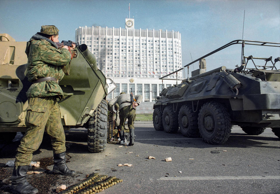 FILE - A Russian army soldier fires his submachine gun covering a fellow soldier who caries ammunition for APC heavy machine gun during the assault aimed to flush out hard-line lawmakers and their supporters inside the parliament building in Moscow on Oct. 4, 1993. The October 1993 violent showdown between the Kremlin and supporters of the rebellious parliament marked a watershed in Russia's post-Soviet history. (AP Photo/Peter Dejong, File)