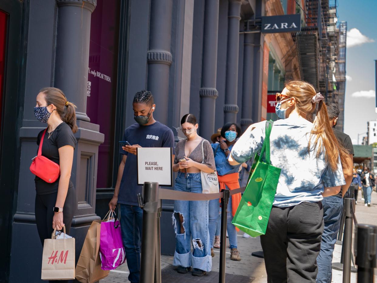 Customers wait in a line before entering a store on Broadway while wearing protective masks in the retail shopping district of the SoHo neighborhood of the Manhattan borough of New York, Friday, May 14, 2021.  (AP)
