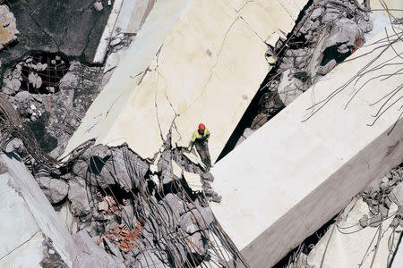 Rescue workers search on the site of the collapsed Morandi Bridge in the port city of Genoa, Italy August 14, 2018. REUTERS/Massimo Pinca