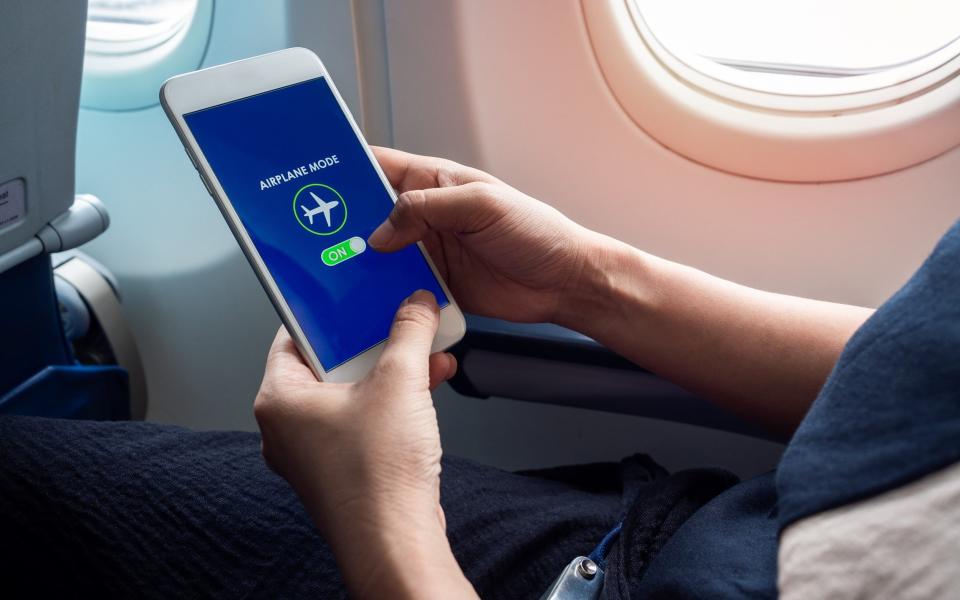 Person turning on airplane mode - Getty