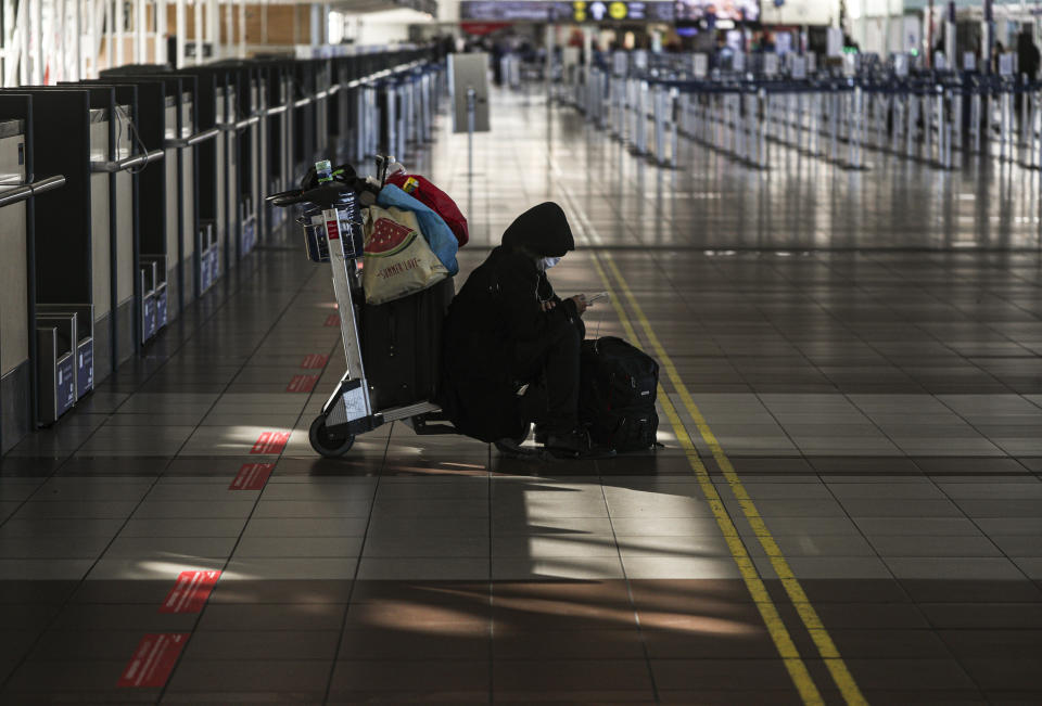 A lone passenger sits near the empty check-in area for Latam airplanes at the Arturo Merino Benitez airport in Santiago, Chile, Tuesday, May 26, 2020. South America’s biggest carrier is seeking U.S. bankruptcy protection as it grapples with a sharp downturn in air travel sparked by the coronavirus pandemic. (AP Photo/Esteban Felix)