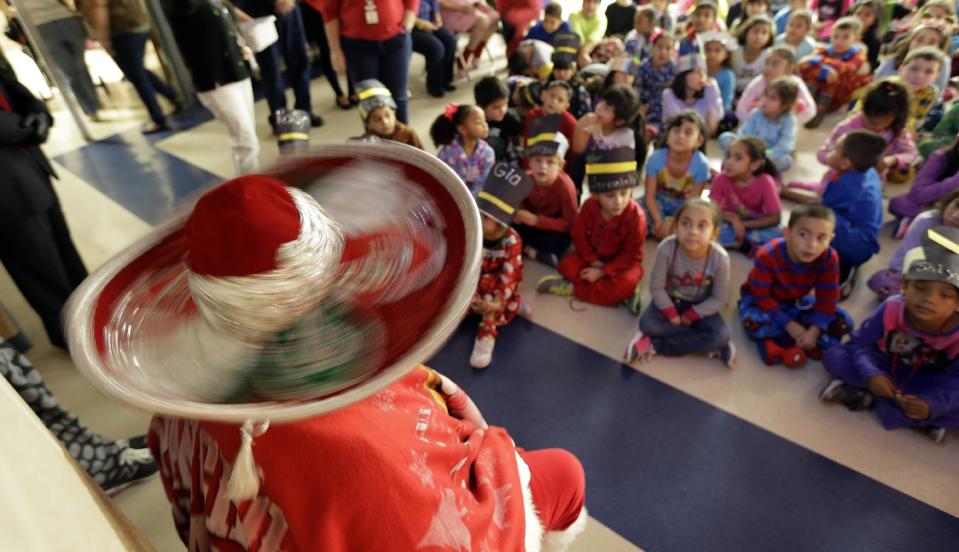 In this Friday, Dec. 20, 2013, photo, the sombrero of Pancho Claus, Rudy Martinez spins as he visits with students at Knowlton Elementary School, in San Antonio. Pancho Claus, a Tex-Mex Santa borne from the Chicano civil rights movement in the late 1970s and early 1980s, is now an adored Christmas fixture in many Texas cities. (AP Photo/Eric Gay)