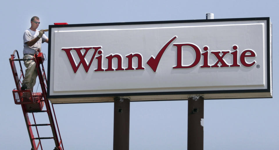 FILE - Mark Moore, of BriteLite Signs, paints a sign with the new Winn-Dixie logo, June 29, 2006, at the headquarters of Winn-Dixie Stores, Inc., in Jacksonville, Fla. Discount grocer Aldi said Wednesday, Aug. 16, 2023, that it plans to buy 400 Winn-Dixie and Harveys supermarkets in the southern U.S. (AP Photo/Oscar Sosa, File)