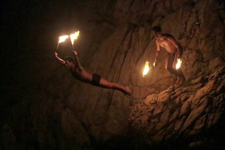 Cliff divers hold torches as they jump at La Quebrada in Acapulco, Mexico