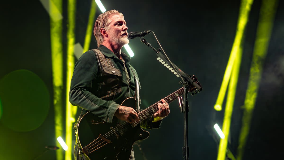  Josh Homme playing guitar on stage. 