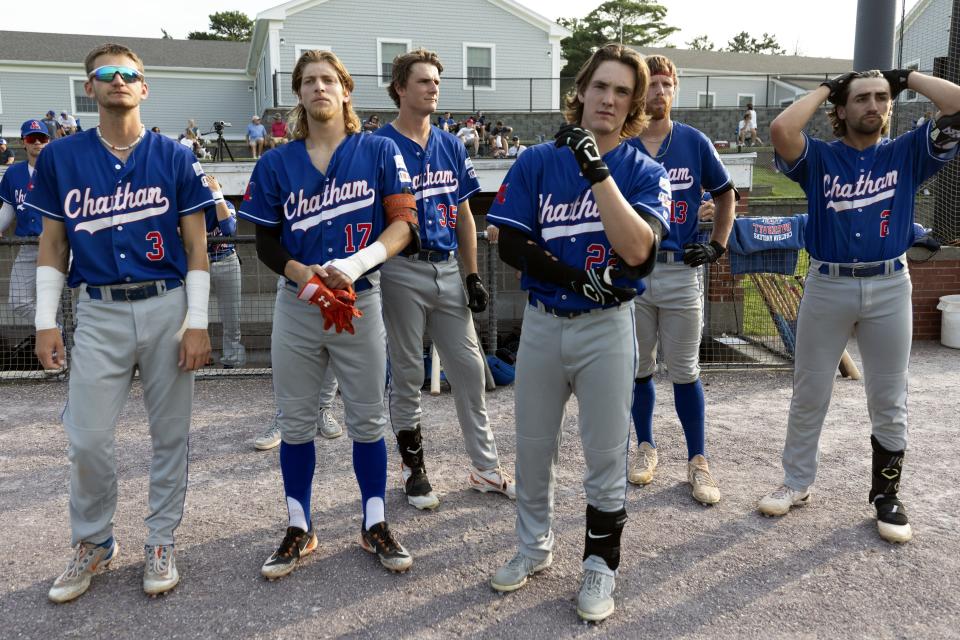 Chatham Anglers players stand in front of their dug out before a Cape Cod League baseball game against the Bourne Braves, Wednesday, July 12, 2023, in Bourne, Mass. For 100 years, the Cape Cod League has given top college players the opportunity to hone their skills and show off for scouts while facing other top talent from around the country. (AP Photo/Michael Dwyer)