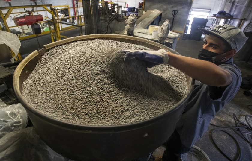 COLTON, CA - OCTOBER 04, 2021:Jonathan Contreras, 28, adds gray coloring, to be mixed in with ground up rubber to make rubber tiles at U.S. Rubber Recycling in Colton. Contreras is a former felon. Employers, now facing severe labor shortages, are starting to tap into hiring former felons. U.S. Rubber is a 25 year old company that has been hiring former felons for years. The company makes use of old tires, grinding them into flooring products, including rubber mats for home gyms which have taken off during the pandemic. (Mel Melcon / Los Angeles Times)