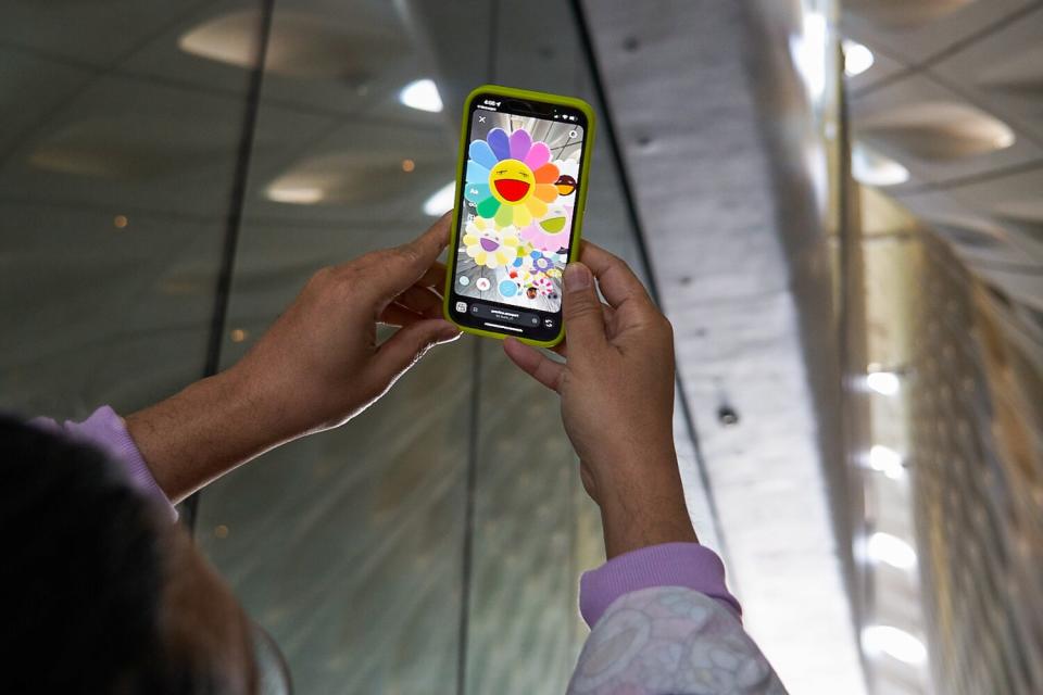 A cell phone is held up to show AR flowers.