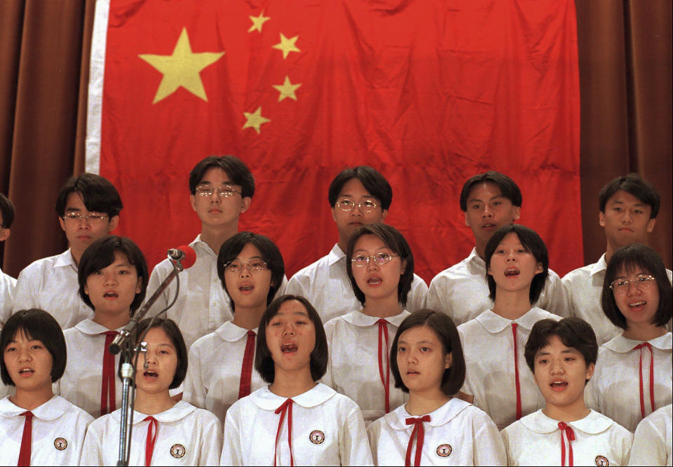 FILE - In this Oct. 1, 1996, file photo, pupils at the pro-China Mongkok Worker's Children School in Hong Kong, sing in front of a Chinese national flag to celebrate China's national day. A year after Beijing imposed a harsh national security law on Hong Kong, the civil liberties that raised hopes for more democracy are fading. (AP Photo/Vincent Yu, File)