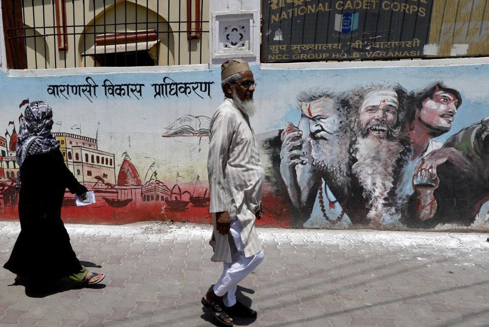 Indian Muslims on way to a polling station to cast their votes walk past a mural showing Hindu holy men during the seventh and final phase of national elections in Varanasi, India, Sunday, May 19, 2019. Indians are voting in the seventh and final phase of national elections, wrapping up a 6-week-long long, grueling campaign season with Prime Minister Narendra Modi’s Hindu nationalist party seeking reelection for another five years. Counting of votes is scheduled for May 23. (AP Photo/Rajesh Kumar Singh)