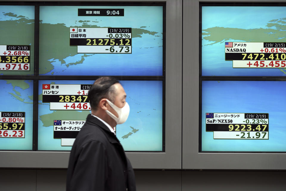 A man walks past an electronic stock board showing Japan's Nikkei 225 index and other country's index at a securities firm in Tokyo Tuesday, Feb. 19, 2019. Asian shares are mostly higher as Chinese and U.S. officials prepare for trade talks in Washington this week. (AP Photo/Eugene Hoshiko)