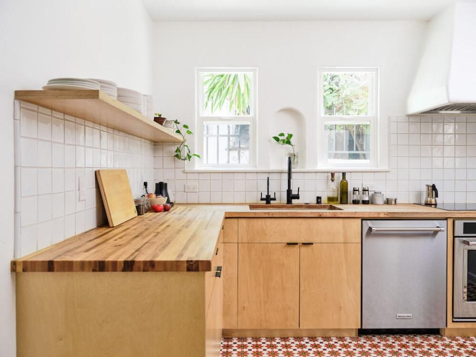 Bright Scandinavian-style kitchen with a white tile backsplash and light wood countertops, cabinets, and shelving