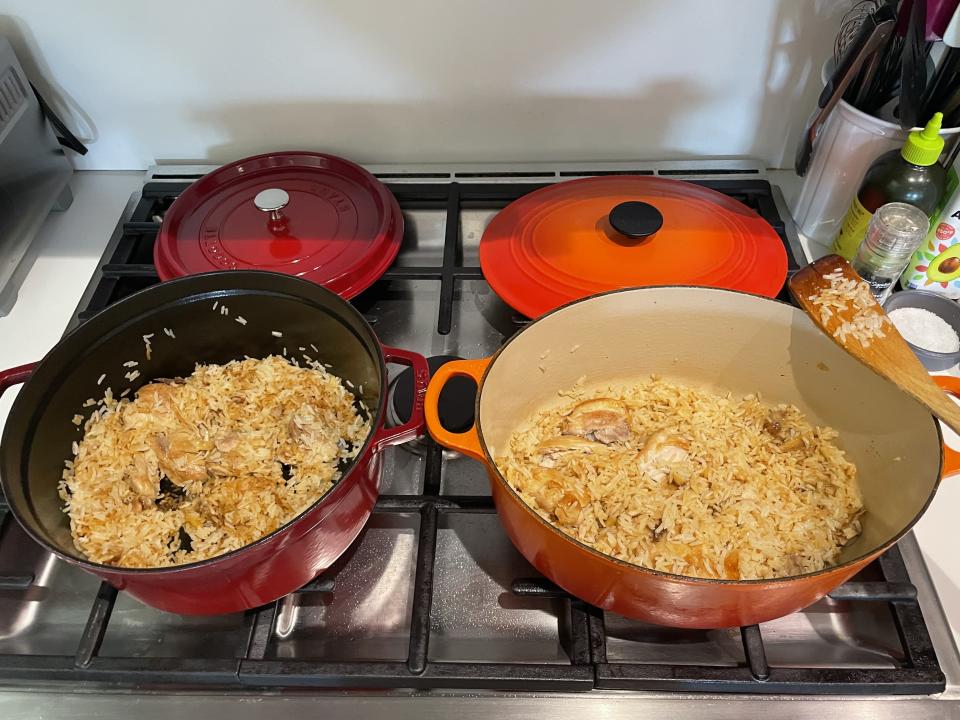 Staub Dutch next to the Le Creuset Dutch oven on a stovetop, both with chicken and rice inside