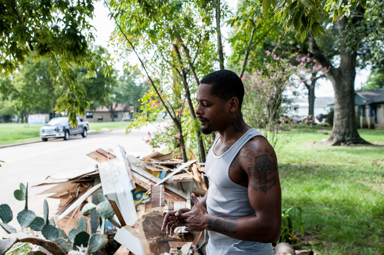 Damion Lasker, 24, stands next to debris on Sunday taken from his mother's flooded home in Katy, Texas, west of Houston. Houses on every street in this town have similar piles waiting for pickup. (Photo: JOSEPH RUSHMORE FOR HUFFPOST)