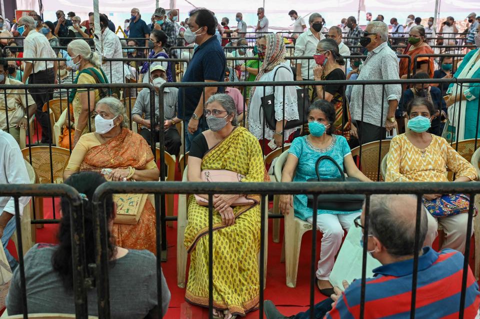 People line up to receive a dose of a COVID-19 vaccine at a vaccination center in Mumbai, India on Tuesday.