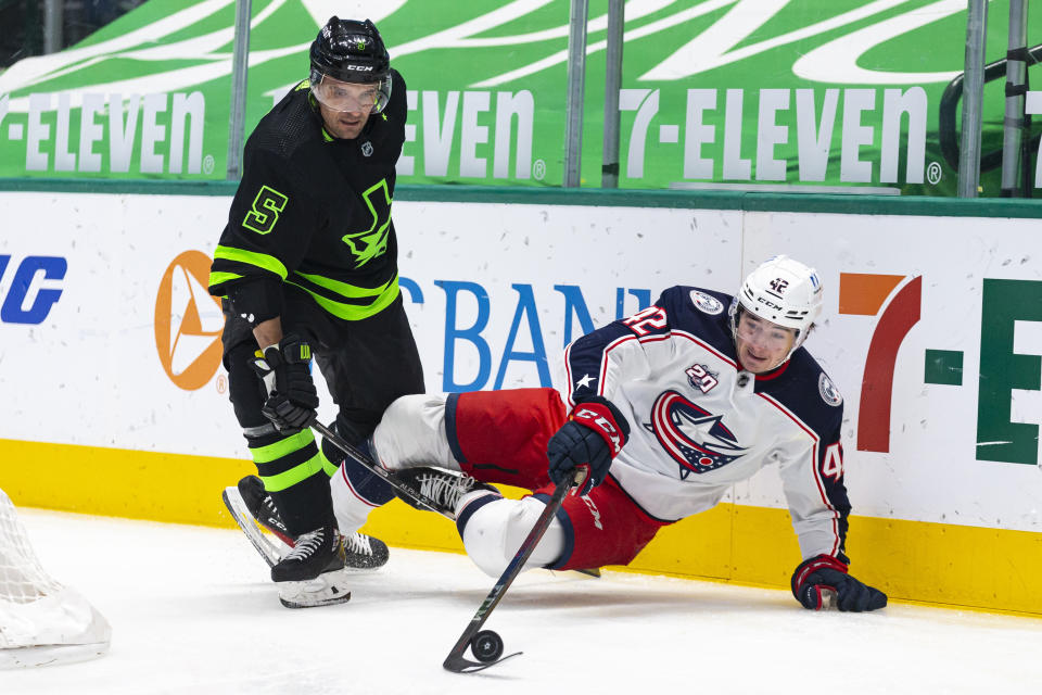 Columbus Blue Jackets center Alexandre Texier (42) dives for a loose puck in front of Dallas Stars defenseman Andrej Sekera (5) during the first period of an NHL hockey game Saturday, April 17, 2021, in Dallas. (AP Photo/Sam Hodde)