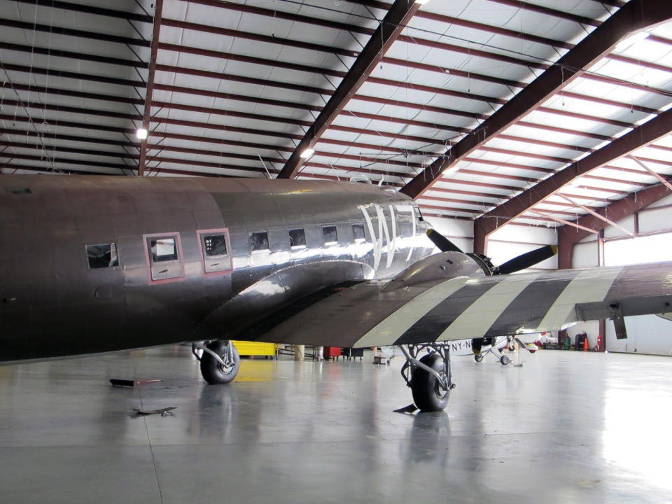 This photo taken March 6, 2014, shows a World War II-era Douglas C-47, housed at the National Warplane Museum in Geneseo, N.Y., and pilot Naomi Wadsworth. At the invitation of the French government, the airplane will return to France in June to participate in celebrations marking the 70th anniversary of the D-Day invasion of Normandy. The airplane, known as Whiskey 7 because of its markings, is one of the original troop carriers that dropped paratroopers in advance of the amphibious invasion. In June it will recreate its role and drop paratroopers over the original drop zone in Sainte-Mere-Eglise. (AP Photo/Carolyn Thompson)