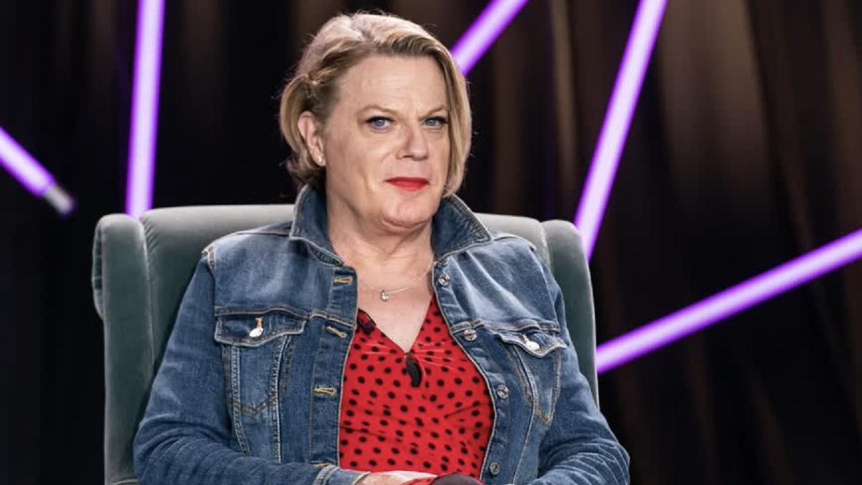 Suzy Eddie Izzard wearing a red top and blue denim jacket