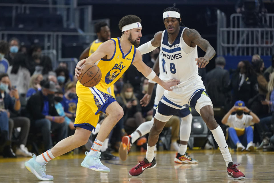 Golden State Warriors guard Klay Thompson, left, drives to the basket against Minnesota Timberwolves forward Jarred Vanderbilt (8) during the first half of an NBA basketball game in San Francisco, Thursday, Jan. 27, 2022. (AP Photo/Jeff Chiu)