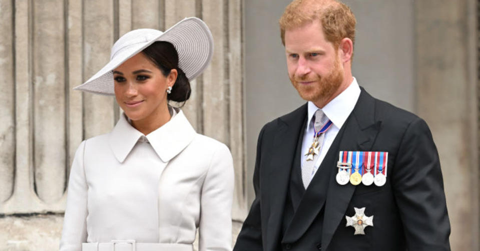 Meghan Markle wears a big white hat and white coat, Prince Harry wears a black suit with medals