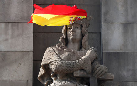 A Spanish flag hangs over the face of a figure representing one of the four realms of Spain on the statue to Columbus in Barcelona, Spain, October 11, 2017. REUTERS/Gonzalo Fuentes